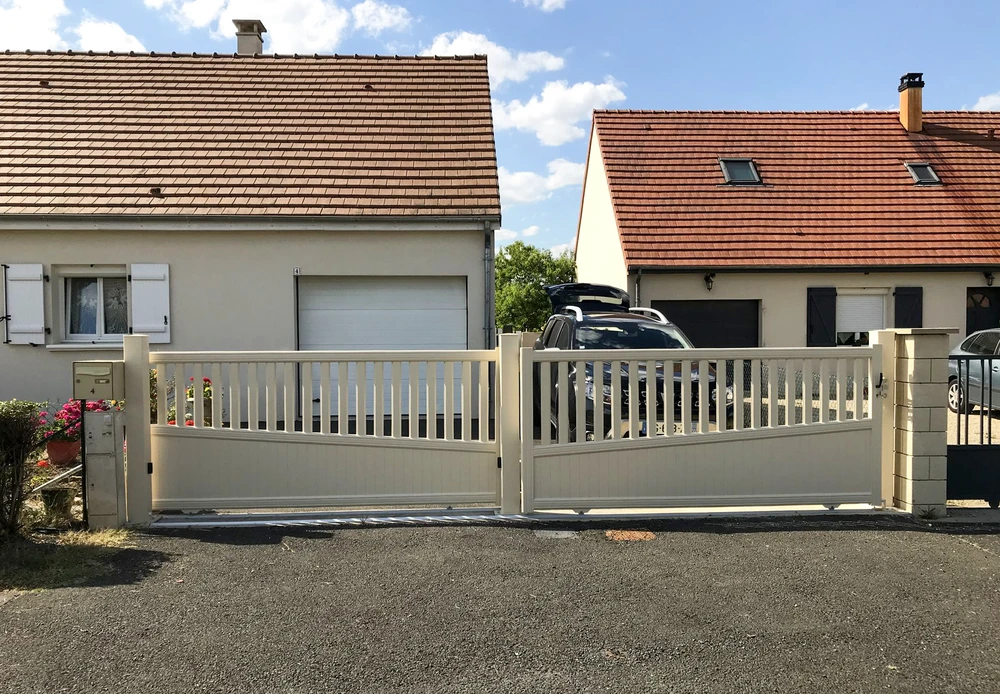 Portail coulissant double vantaux en aluminium laqué blanc cassé, style contemporain avec lames verticales ajourées et bandeau bas plein à courbe supérieure
