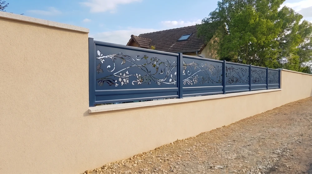 Portillon de jardin moderne en aluminium laqué gris, monté entre deux piliers en pierre naturelle