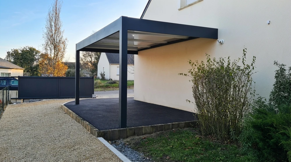Pergola bioclimatique aluminium anthracite à lames orientables installée en terrasse, adossée à une maison de caractère en pierre