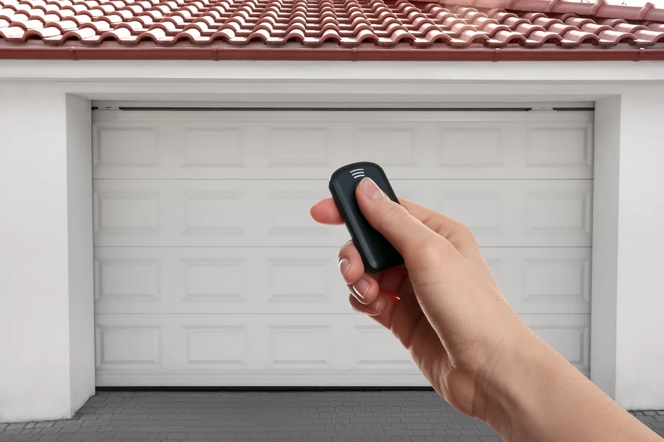 Façade extérieure moderne d'une maison contemporaine avec porte de garage sectionnelle anthracite et portillon assorti intégrés dans un mur en béton beige