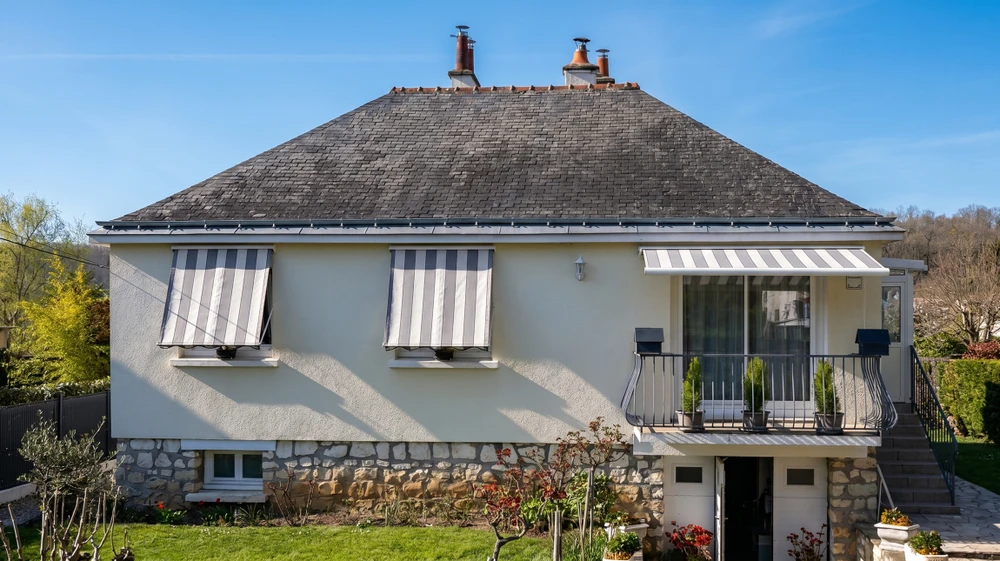 Travailleur en uniforme à l'aide d'une bande de mesure lors de l'installation de stores de fenêtre horizontaux à l'intérieur